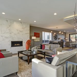 Large luxury home interior with open floor plan features modern kitchen, spacious dining area and gray and white living room with gorgeous fireplace.
